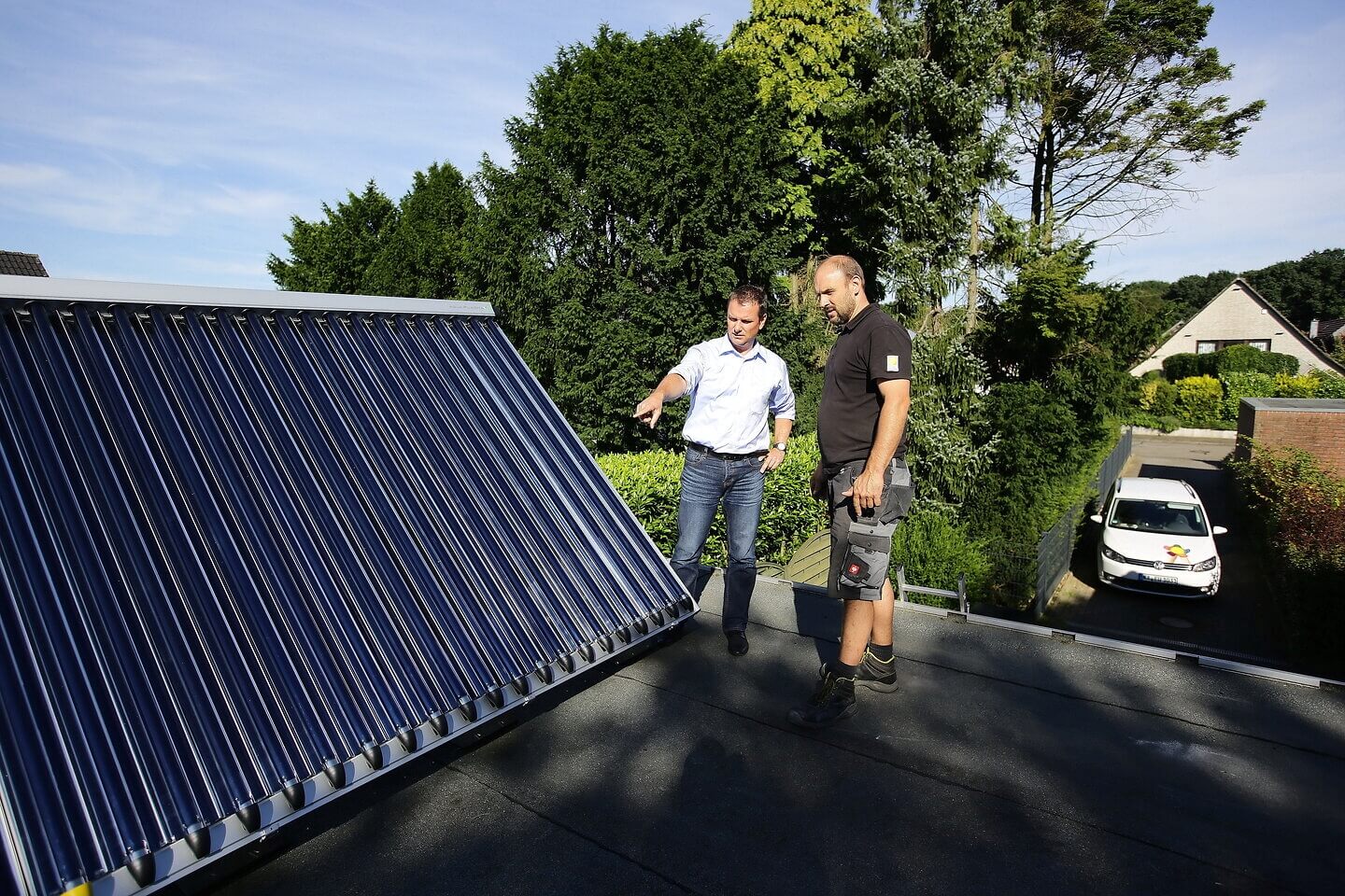 Handwerker gibt dem Hausbesitzer eine Einweisung in die neue Solarthermie-Anlage auf dem Dach seiner Garage. 