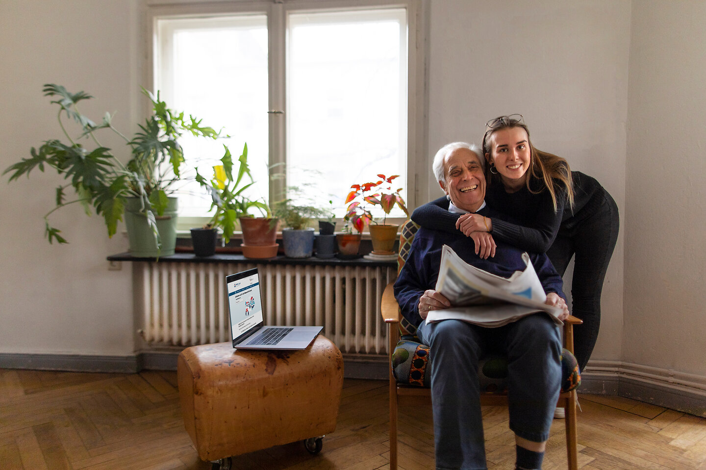 Älterer Mann wird von einer jungen Frau umarmt.