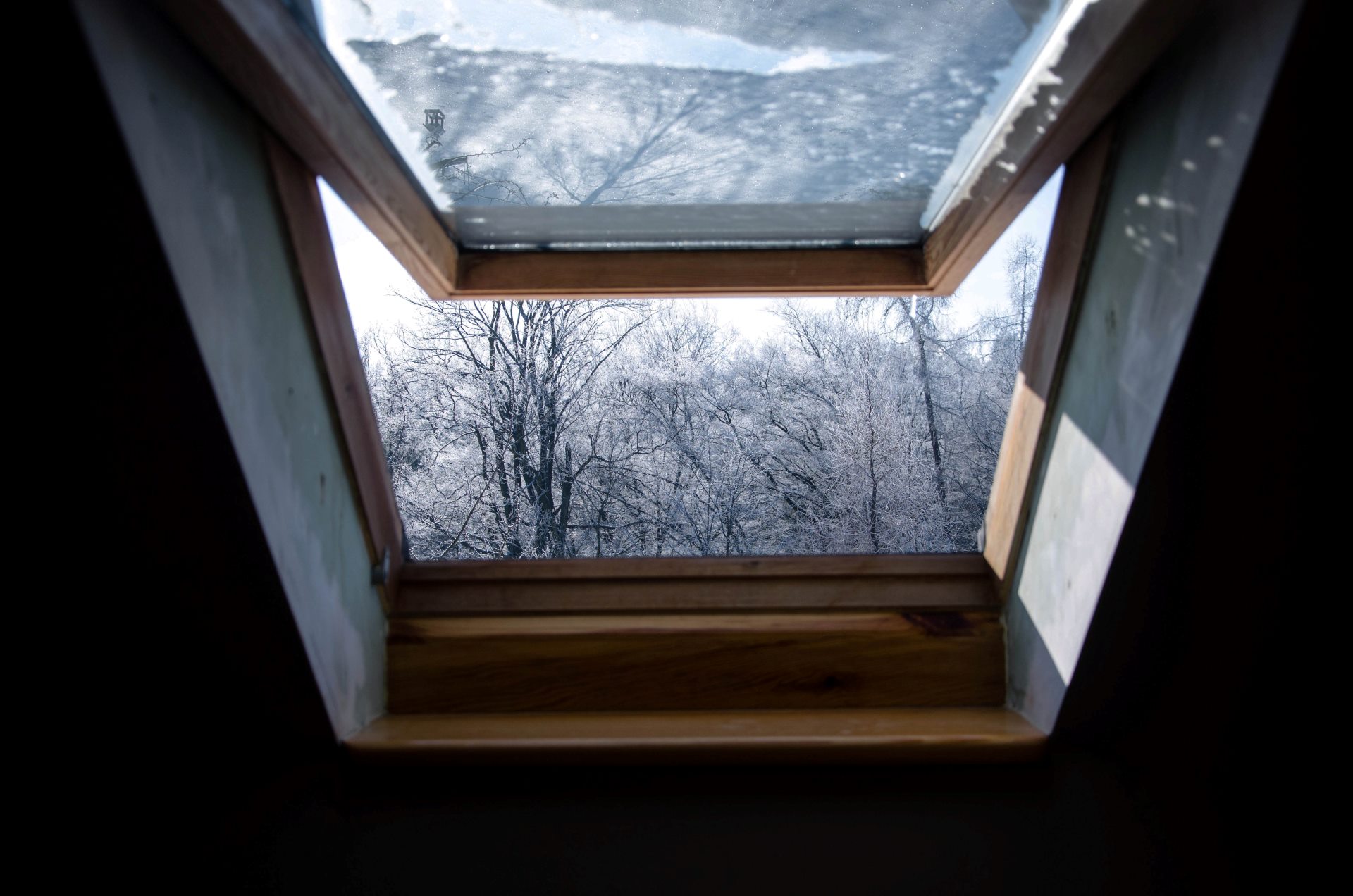 Das Bild zeigt den Blick durch ein offenes Fenster in die Schneelandschaft