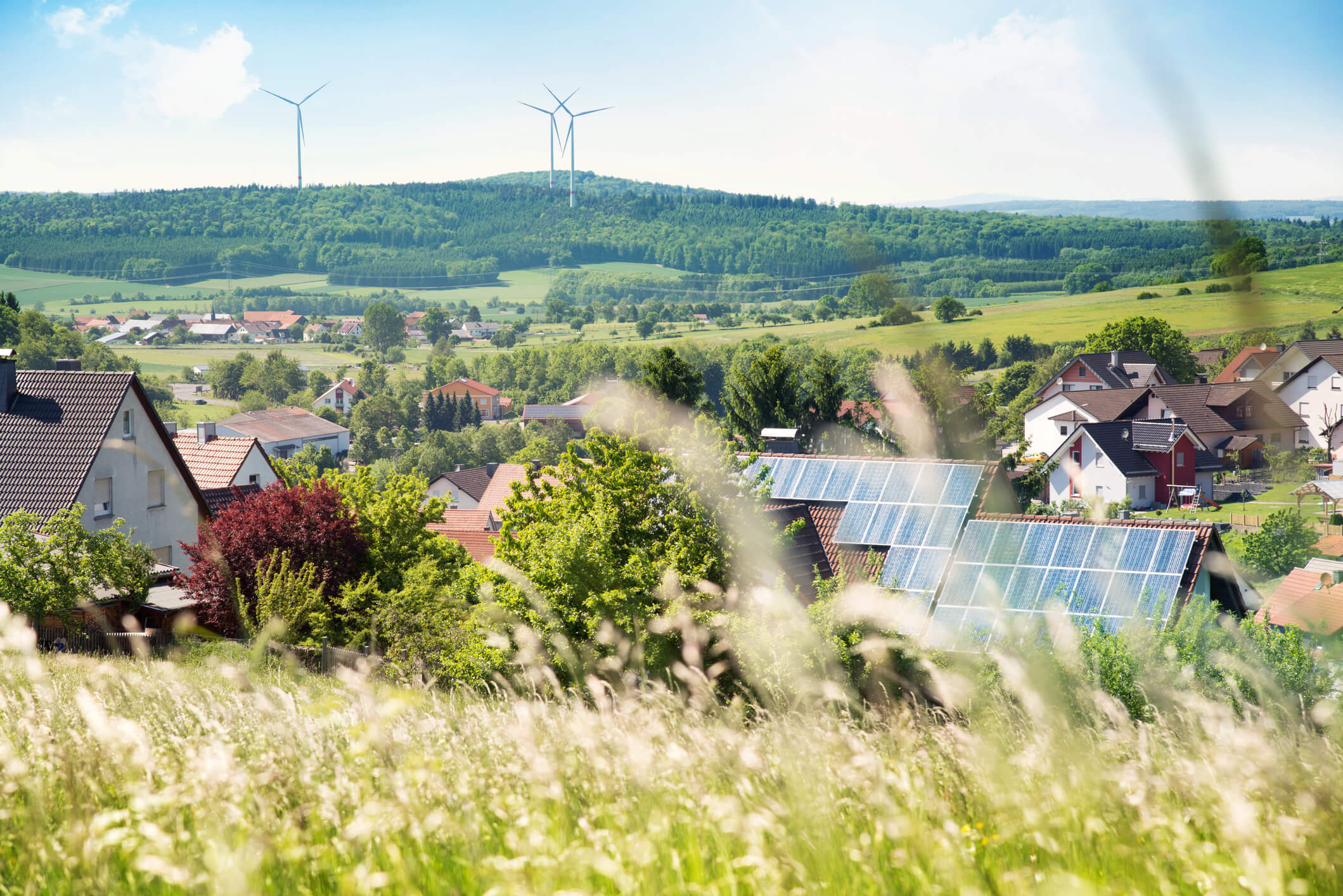 Haus mit Solarzellen auf dem Dach und Windturbinen