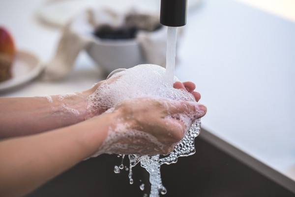 Hände mit Seifenschaum unter fließendem Wasser