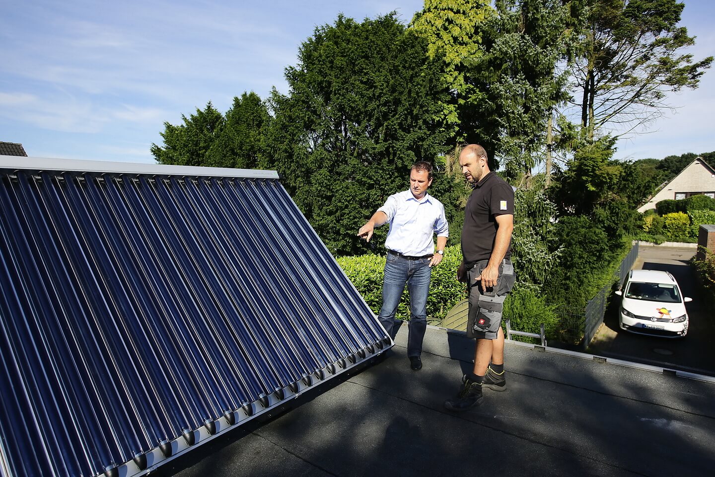 Handwerker gibt dem Hausbesitzer eine Einweisung in die neue Solarthermie-Anlage auf dem Dach seiner Garage. 