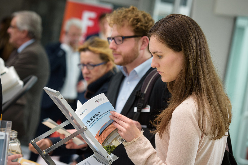 Eine Frau an einem Messestand mit der Fördermittel-Broschüre von co2online