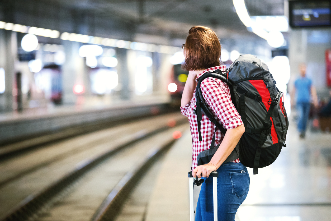 Eine Frau mit Reiserucksack am Bahnsteig