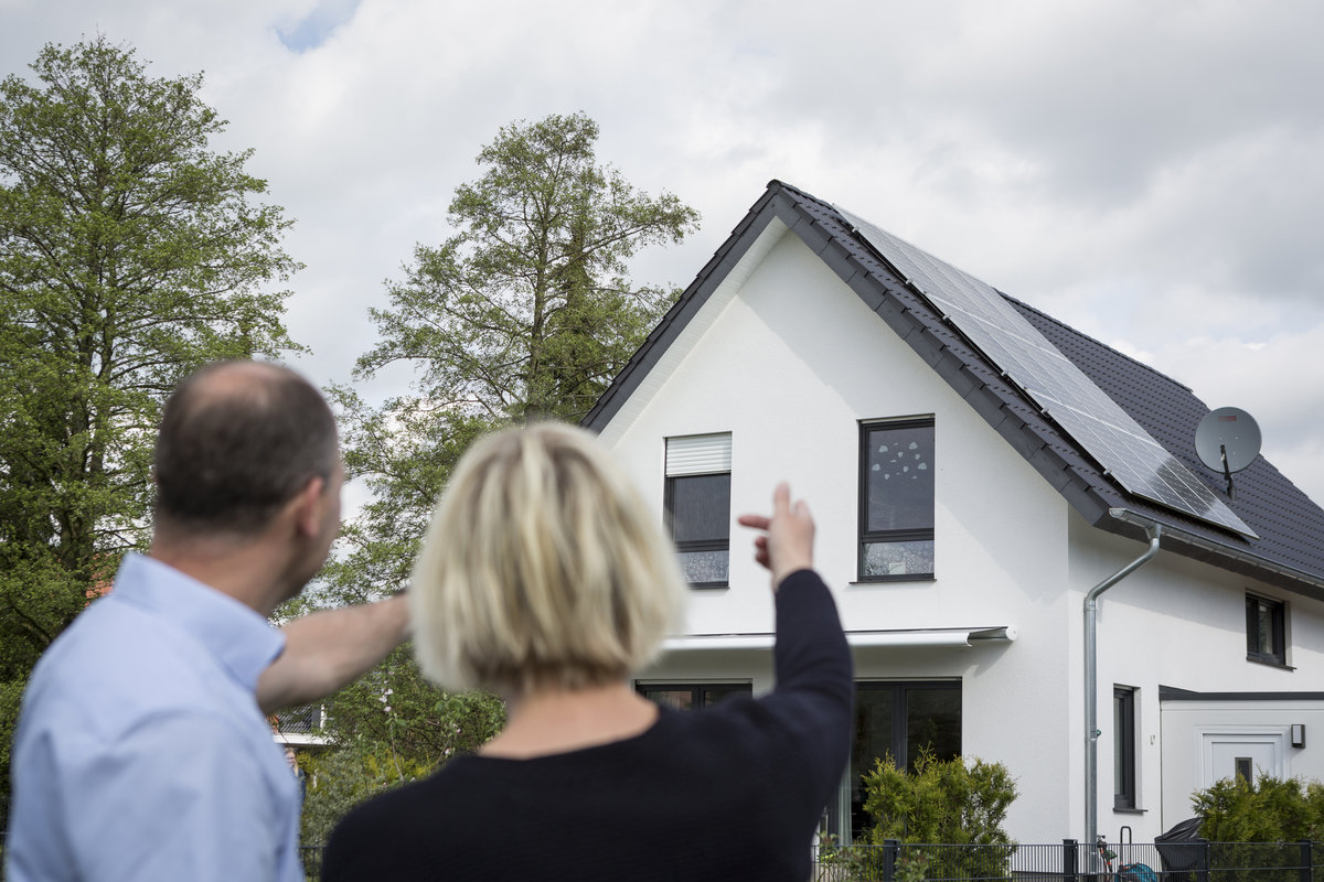 Zwei Personen zeigen auf eine Photovoltaikanlage. 