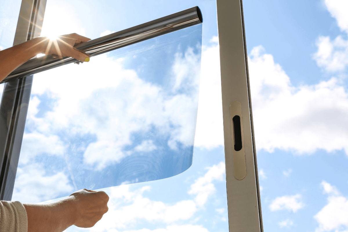 Mensch hält Sonnenschutzfolie ans Fenster