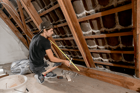 Auf dem Foto ist ein Handwerker beim Dachdämmen abgebildet.