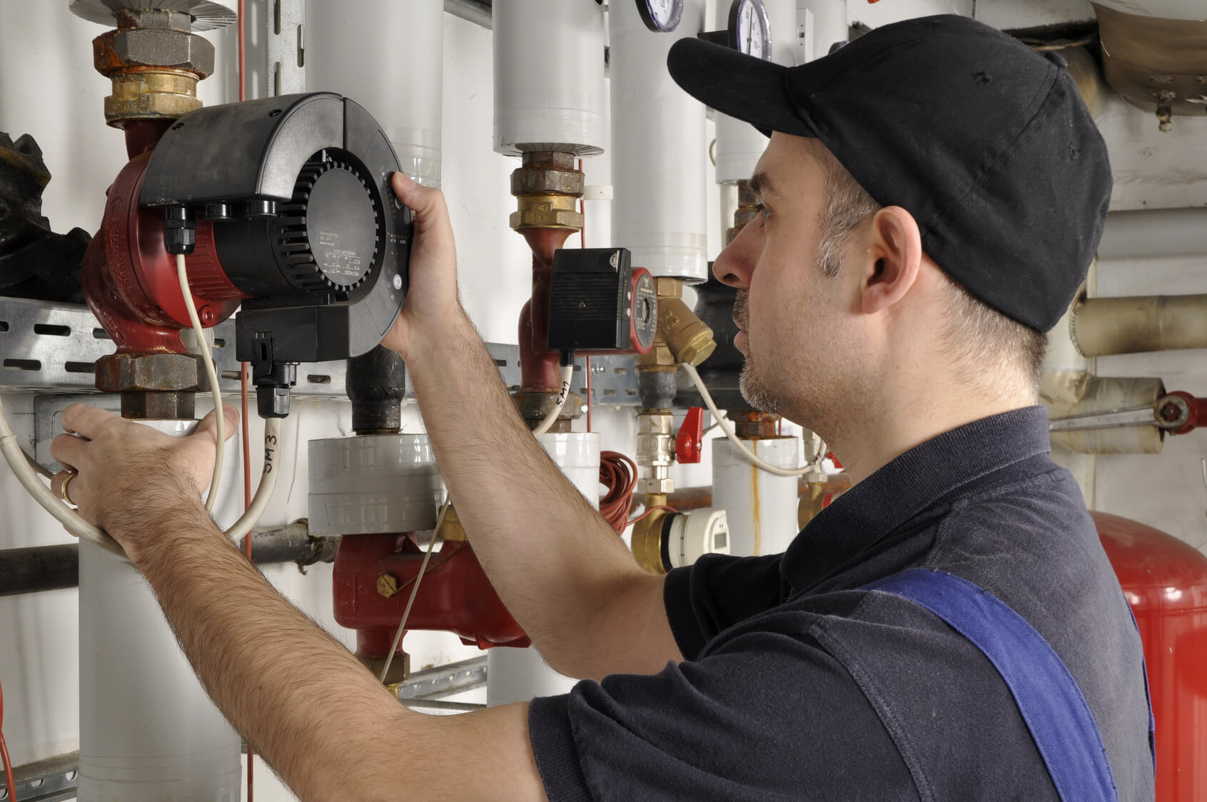 Ein Handwerker arbeitet im Kesselraum an einer Heizung.