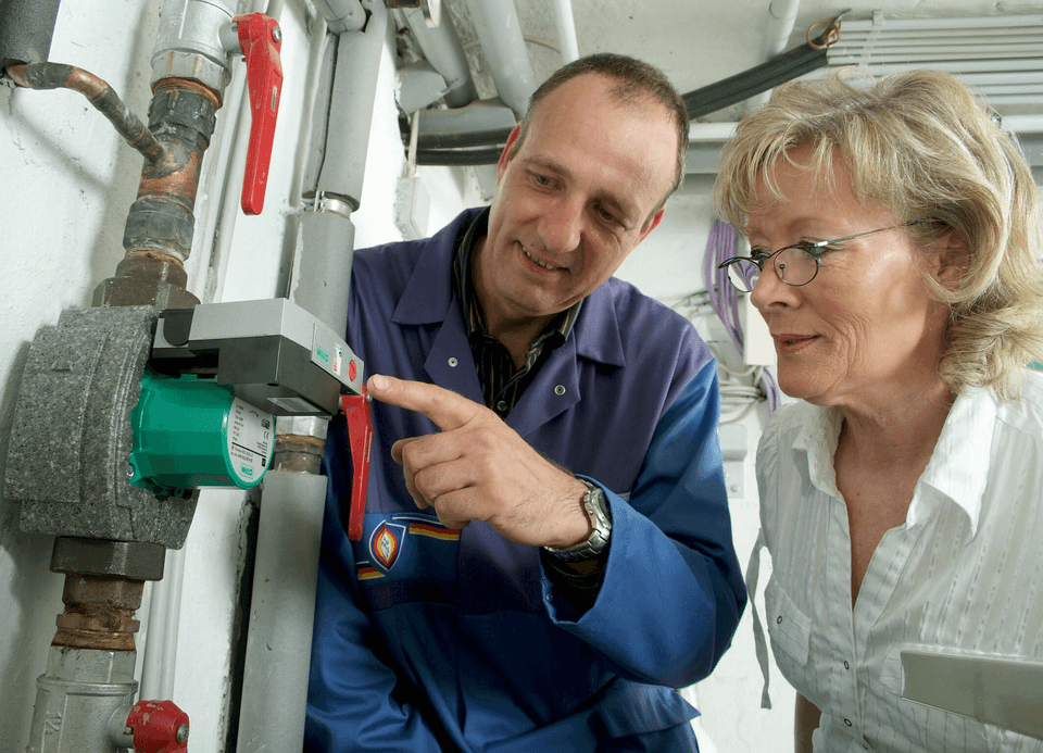 Handwerker erklärt Frau eine Pumpe