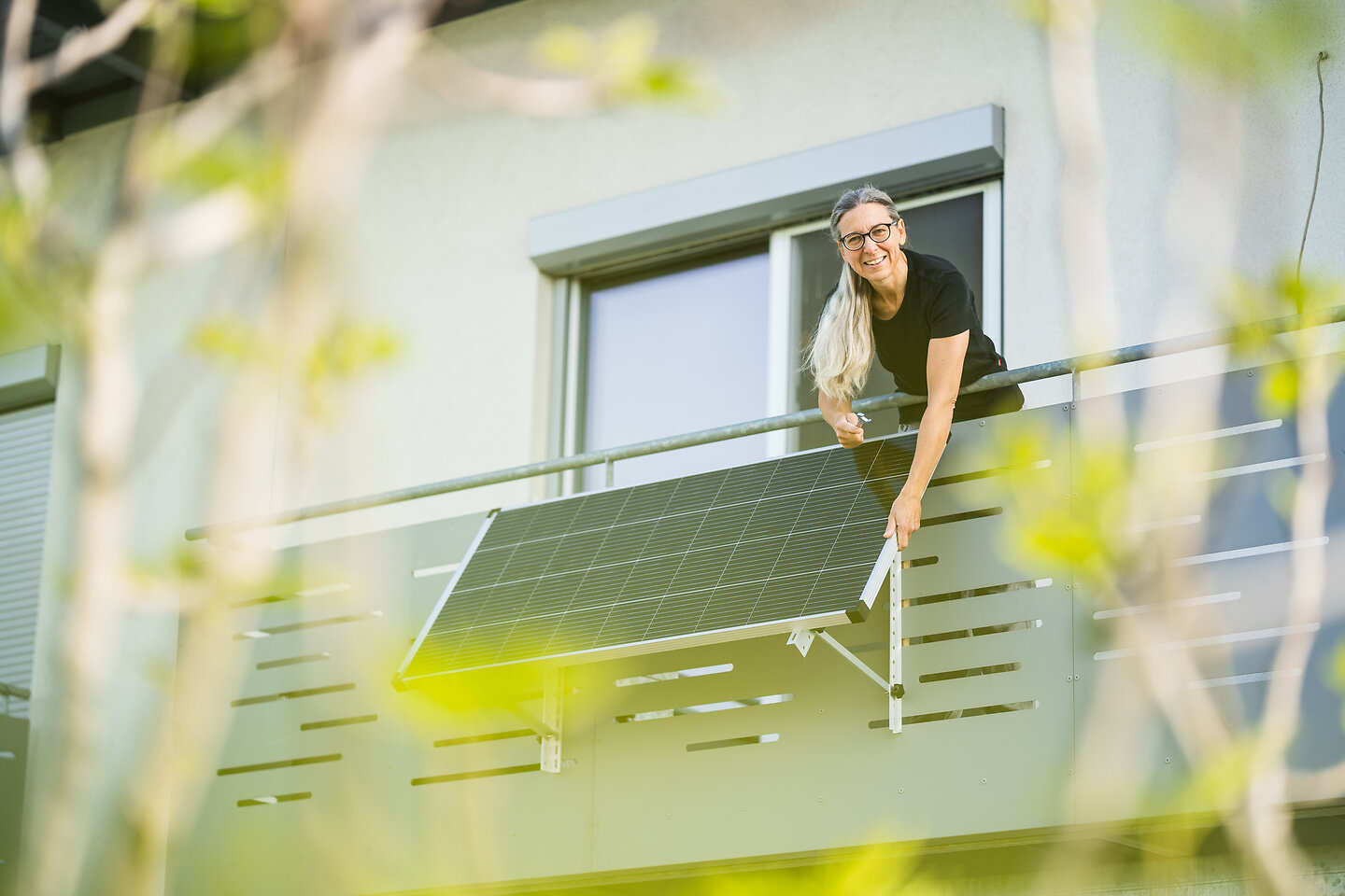 Frau installiert Solarmodule am Balkon