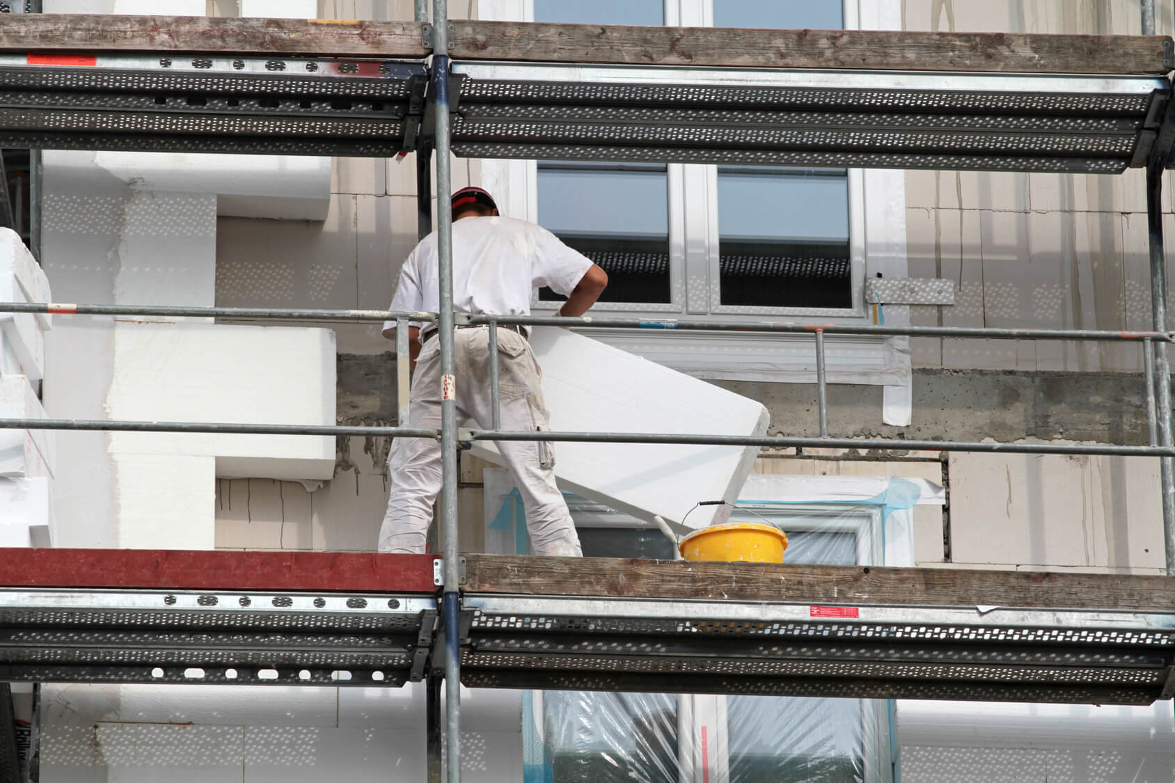 Handwerker mit Dämmstoffplatten auf Gerüst