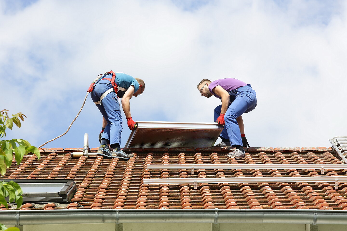 Installation Solarthermie: Männer heben einen Kollektor aufs Dach