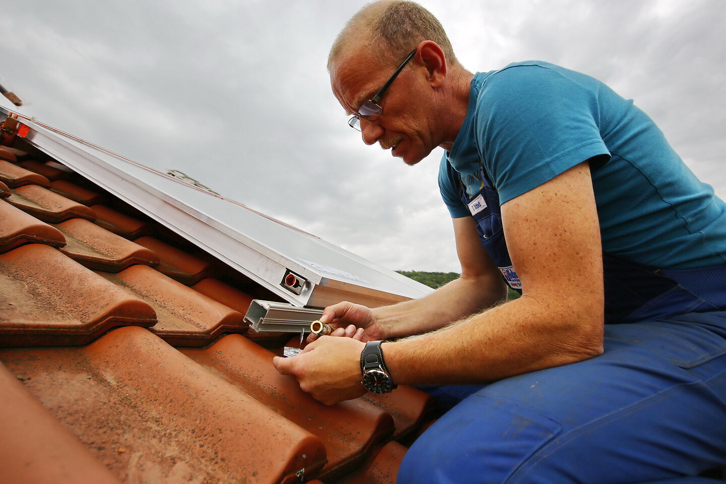 Mann auf Dach schließt Solarkollektor an