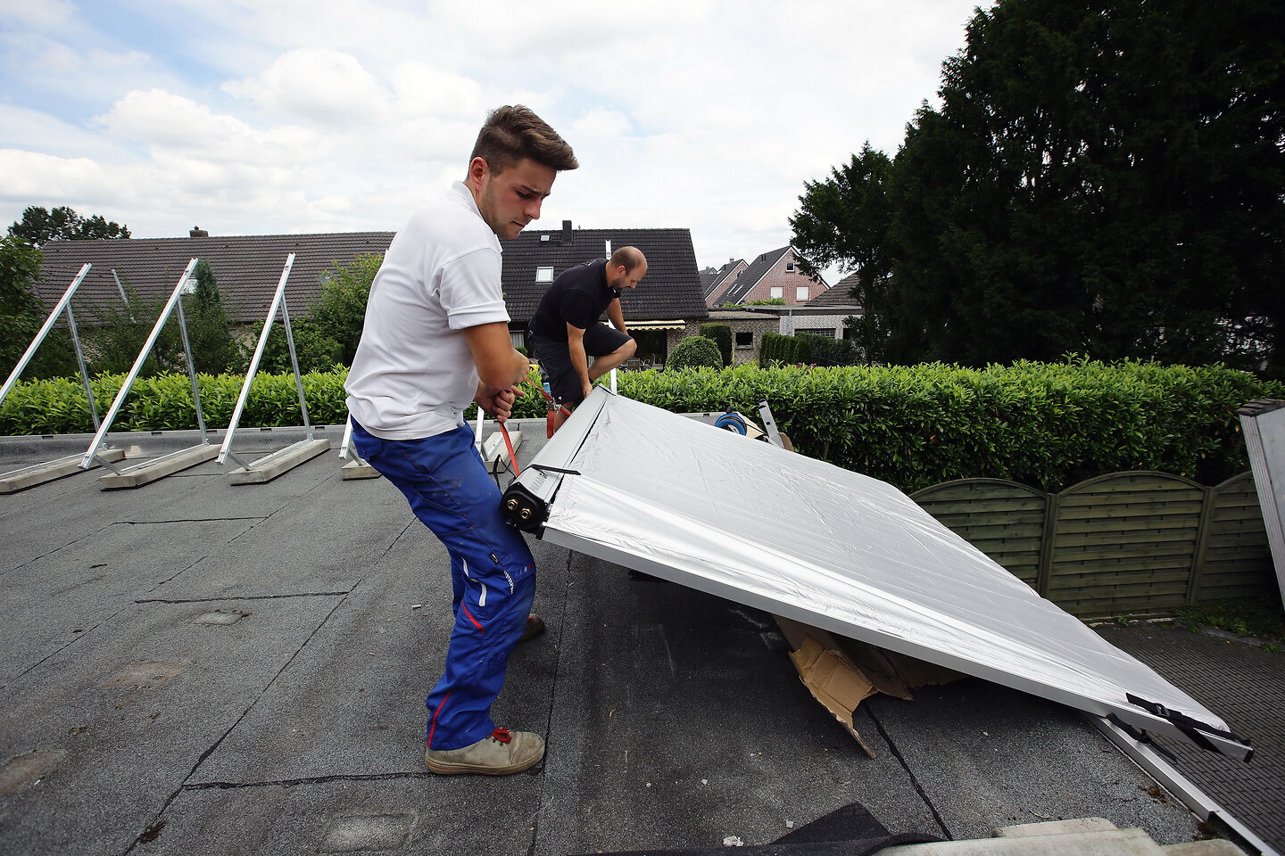 Handwerker tragen Kollektoren aufs Dach.