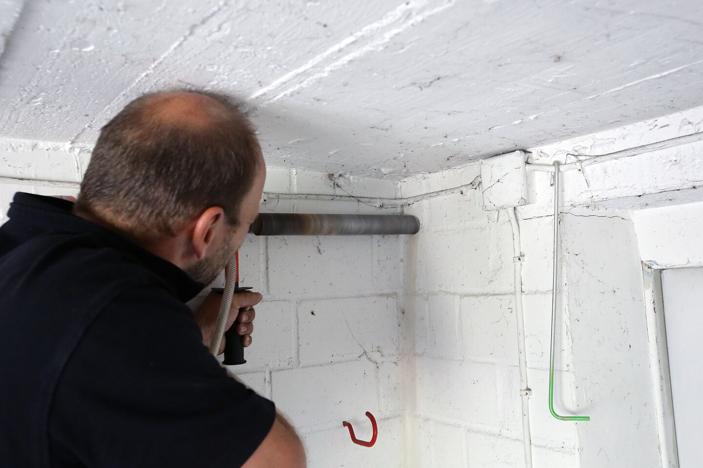 Handwerker bohrt Loch für Solarleitung.