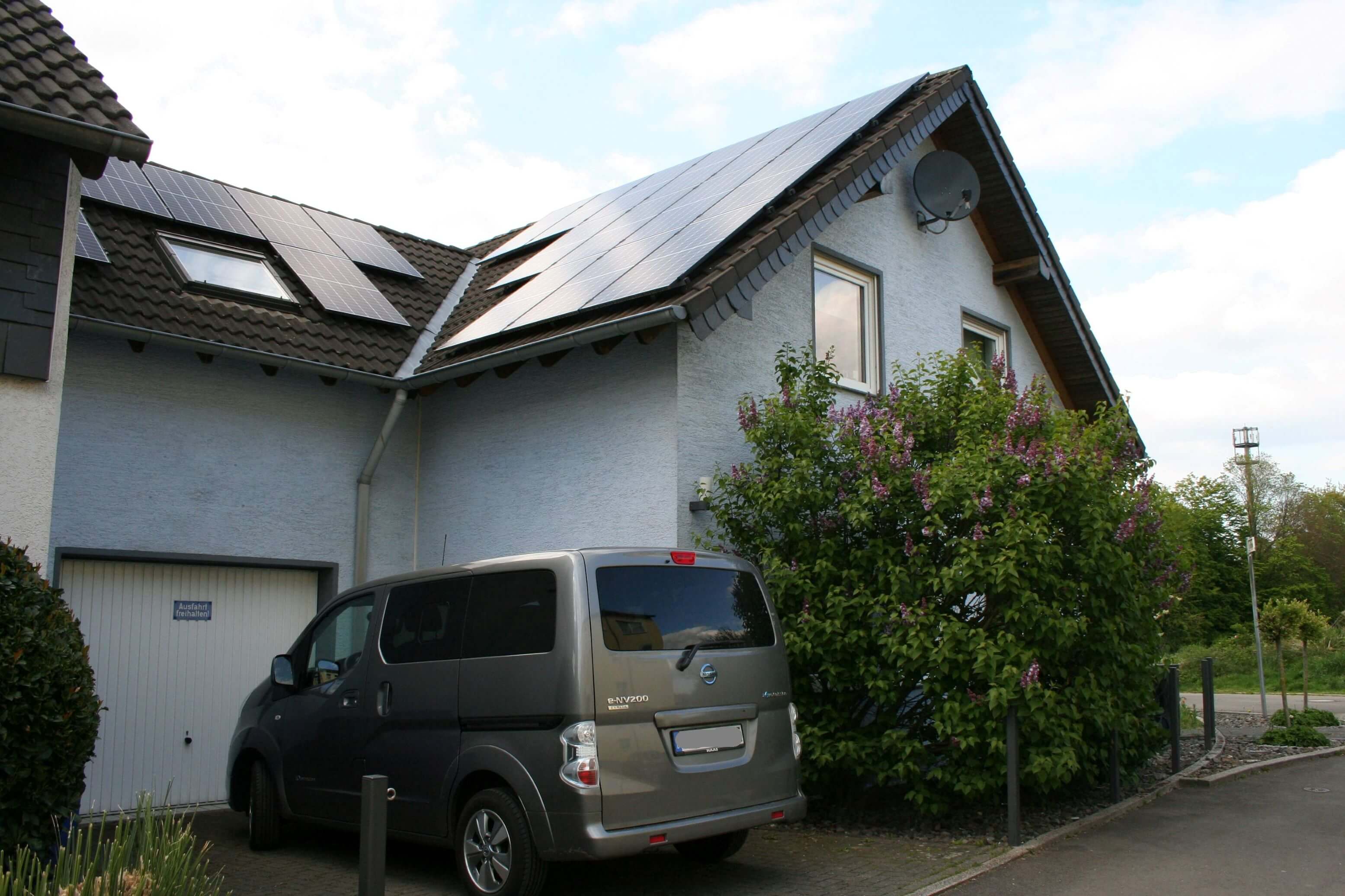 Das Haus von Familie Krüger mit Photovoltaik auf dem Dach und E-Auto in der Einfahrt