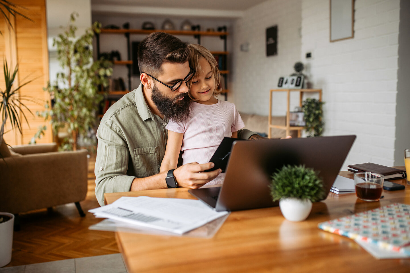 Vater und Tochter am Tisch betrachten Laptop.