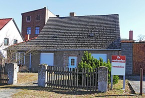 Altbau mit Zu-verkaufen-Schild im Vorgarten