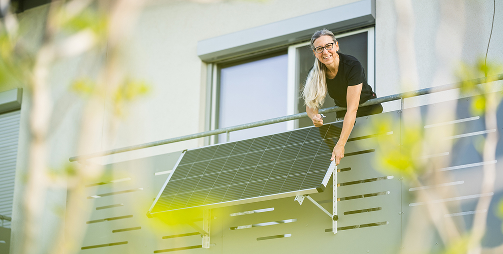 Frau auf einem Balkon mit Photovoltaik-Anlage.